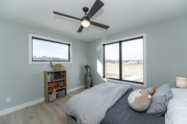 bedroom with ceiling fan, multiple windows, and light hardwood / wood-style flooring