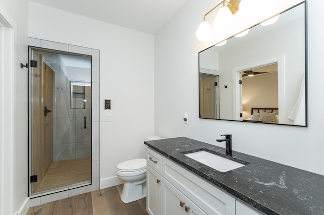 bathroom with vanity, toilet, a shower with shower door, and hardwood / wood-style floors