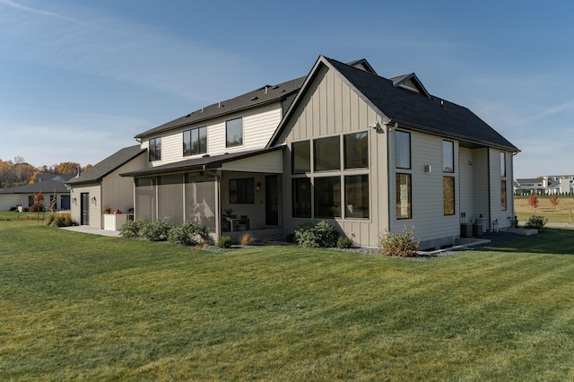 rear view of house featuring a sunroom, central AC unit, and a lawn