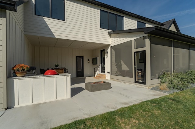 back of property with a patio, a sunroom, and a fire pit