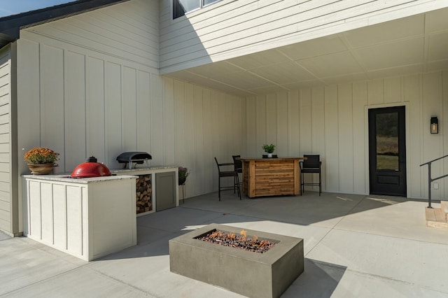 view of patio / terrace featuring an outdoor kitchen, exterior bar, and a fire pit