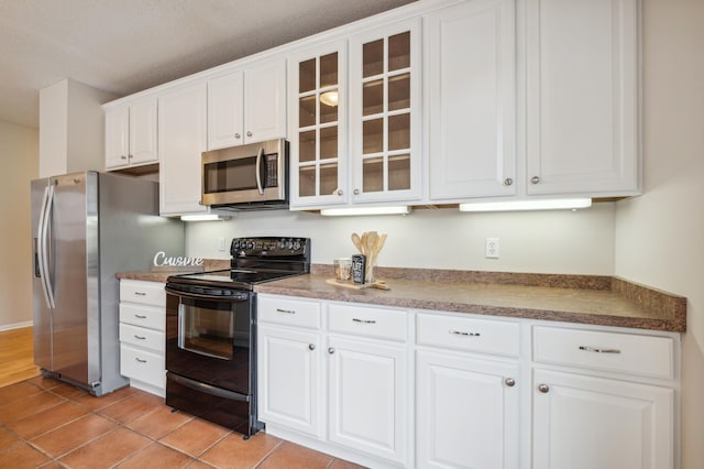 kitchen with white cabinets, light tile patterned floors, a textured ceiling, and appliances with stainless steel finishes