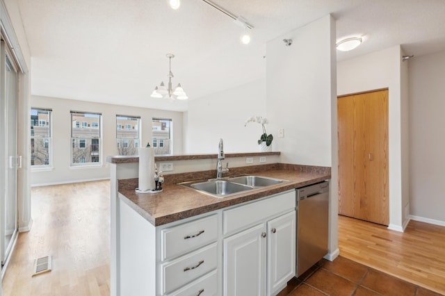 kitchen with dishwasher, white cabinets, hanging light fixtures, sink, and hardwood / wood-style flooring