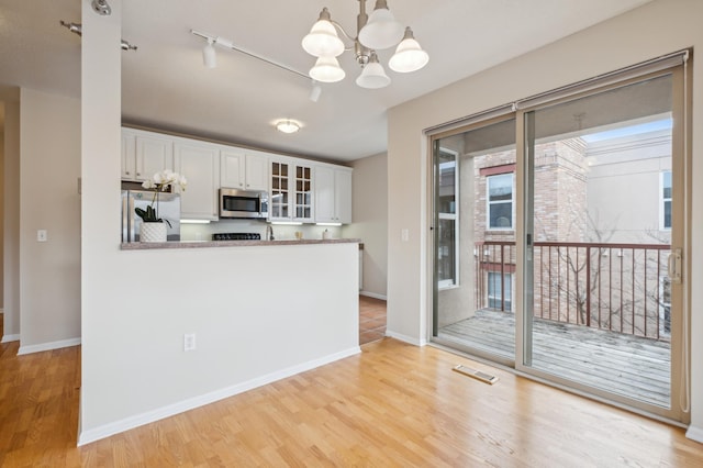 kitchen with white cabinetry, white fridge, light hardwood / wood-style floors, and a notable chandelier