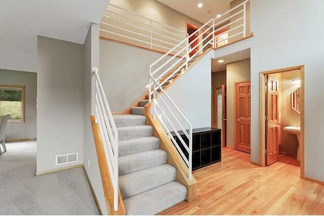 staircase with hardwood / wood-style floors and a high ceiling