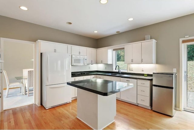 kitchen featuring sink, a center island, light hardwood / wood-style flooring, white appliances, and white cabinets