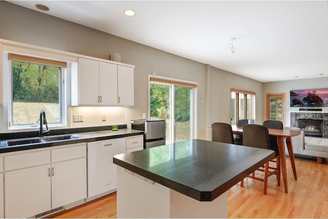 kitchen with white cabinets, a kitchen island, light wood-type flooring, and sink