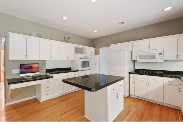 kitchen with white cabinets, light wood-type flooring, white appliances, and a center island