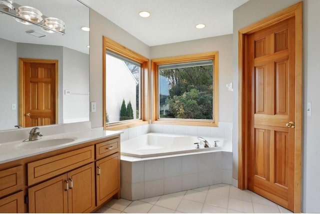 bathroom featuring vanity, tile patterned floors, and tiled tub