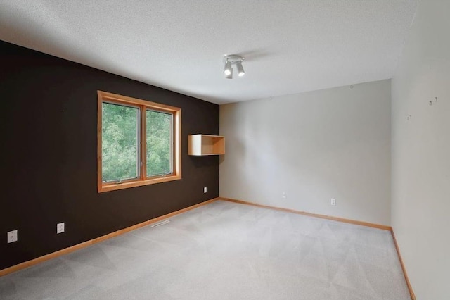 unfurnished room featuring light colored carpet and a textured ceiling