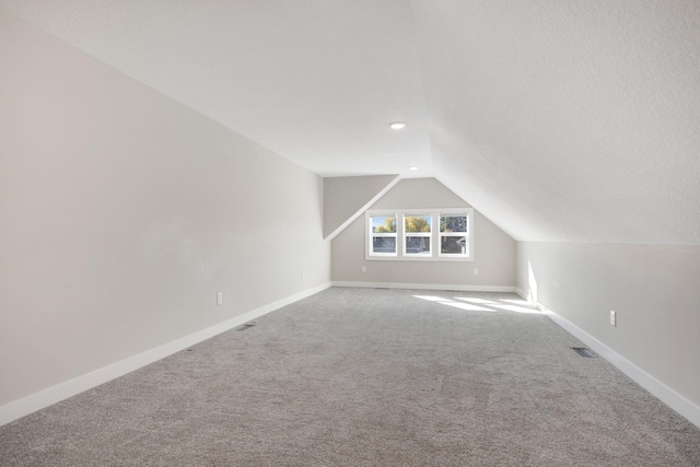 additional living space with a textured ceiling, carpet floors, and lofted ceiling