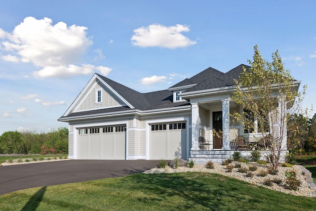 view of front of property featuring a porch, a garage, and a front lawn