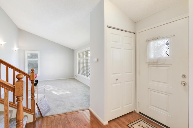 foyer with lofted ceiling, a textured ceiling, and light hardwood / wood-style flooring