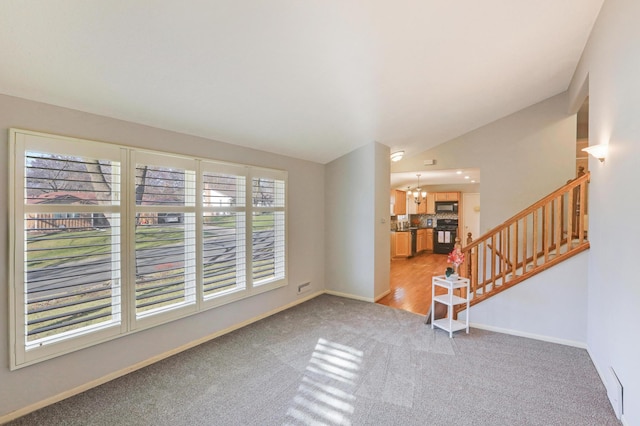 unfurnished room with carpet, vaulted ceiling, a notable chandelier, and a healthy amount of sunlight