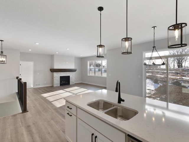 19461 Everglade Path, Farmington, MN 55024 - kitchen with a sink, white cabinetry, light wood finished floors, decorative light fixtures, and a fireplace