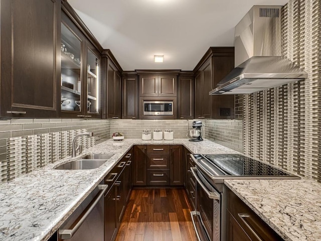 kitchen with dark wood-type flooring, sink, wall chimney exhaust hood, appliances with stainless steel finishes, and tasteful backsplash