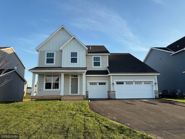 view of front facade featuring a front lawn, covered porch, and a garage