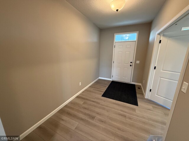 entryway featuring light wood-type flooring and a textured ceiling