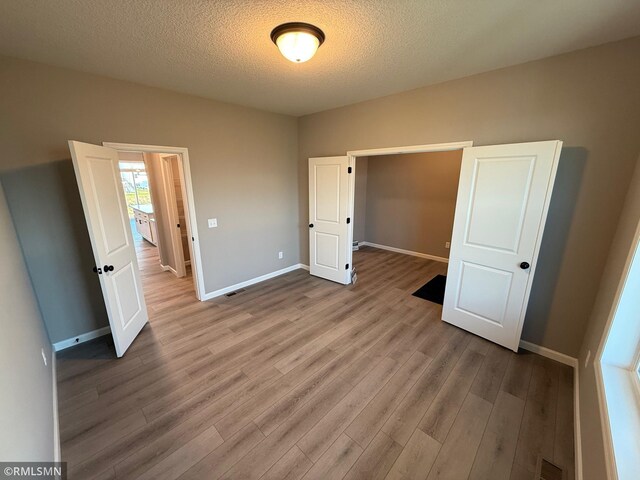 unfurnished bedroom with light hardwood / wood-style floors and a textured ceiling