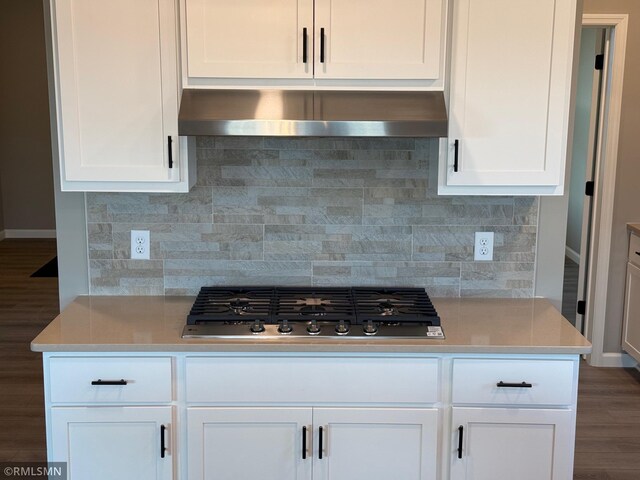 kitchen featuring white cabinetry, wall chimney exhaust hood, dark wood-type flooring, and stainless steel gas stovetop