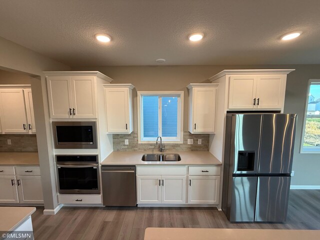 kitchen featuring backsplash, white cabinetry, sink, and stainless steel appliances