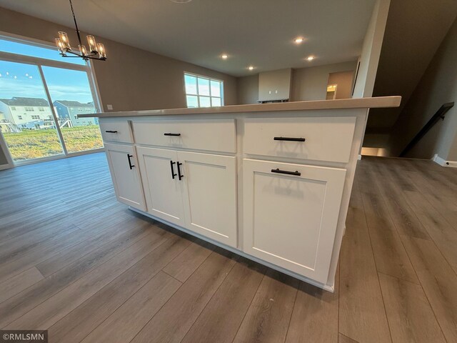 kitchen featuring a wealth of natural light, a kitchen island, white cabinets, and light wood-type flooring