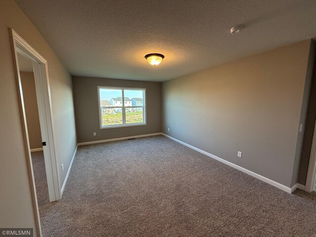 carpeted empty room featuring a textured ceiling