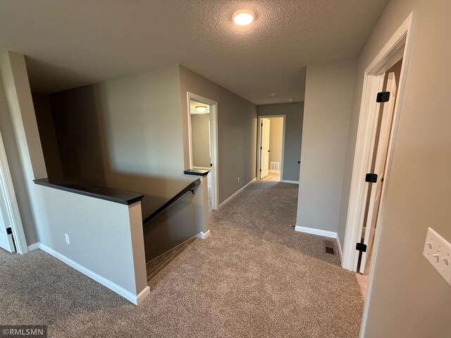 corridor with light colored carpet and a textured ceiling