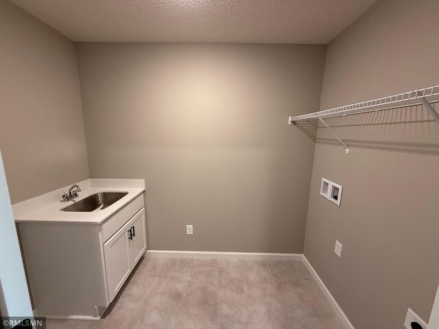 laundry room with cabinets, light carpet, sink, washer hookup, and a textured ceiling