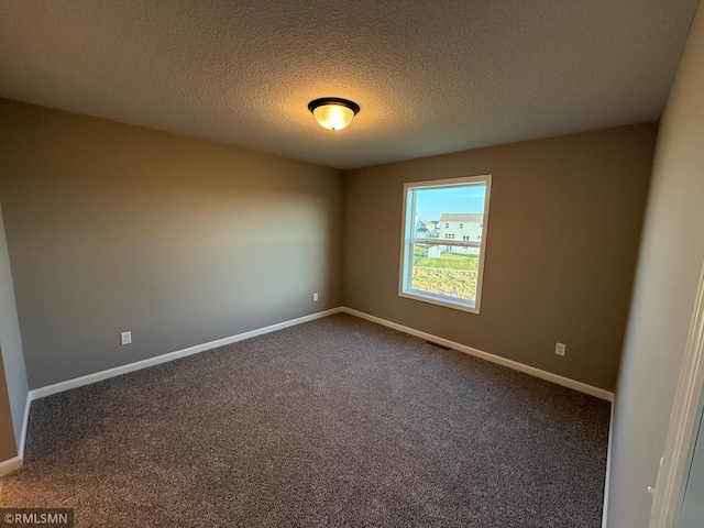 unfurnished room with dark carpet and a textured ceiling