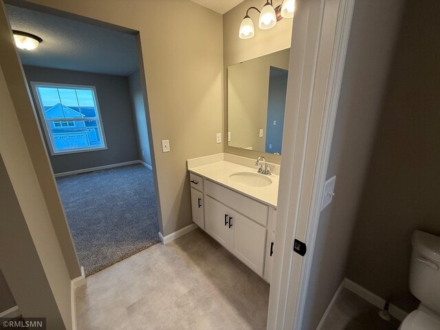 bathroom featuring vanity, a textured ceiling, and toilet