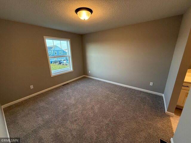 spare room featuring carpet and a textured ceiling