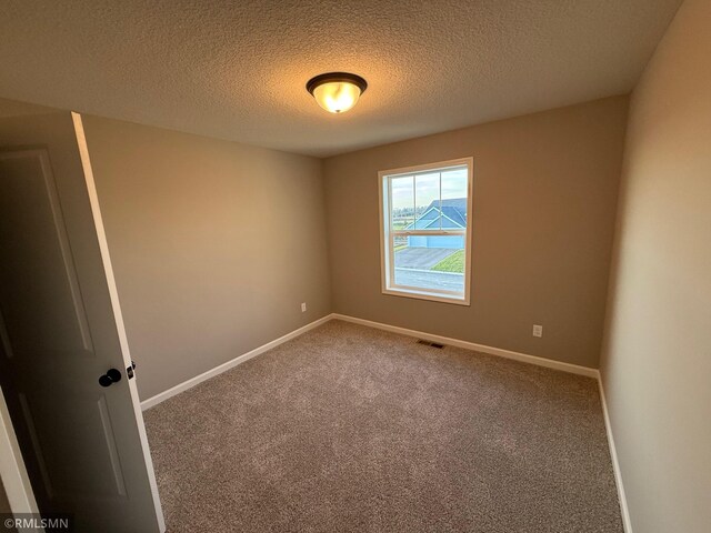 carpeted spare room with a textured ceiling