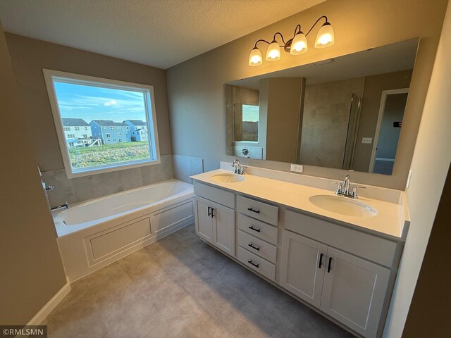 bathroom featuring vanity, a bath, and a textured ceiling