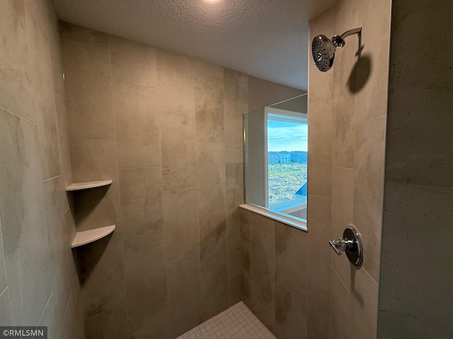 bathroom with tiled shower and a textured ceiling