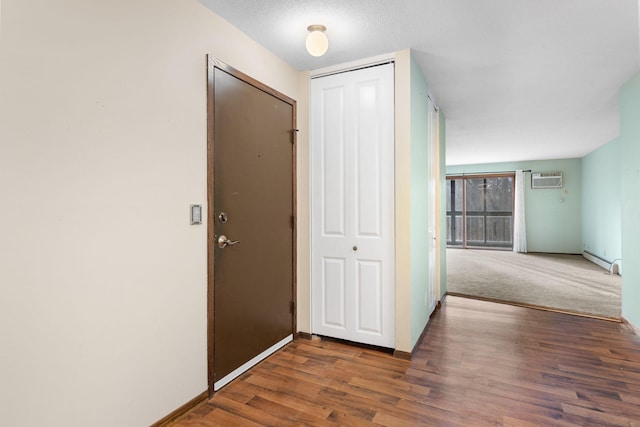 hall featuring a wall mounted AC, dark hardwood / wood-style flooring, a textured ceiling, and a baseboard heating unit