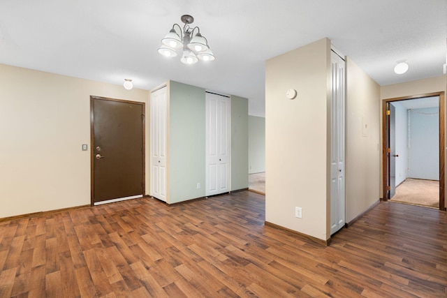 empty room featuring dark hardwood / wood-style flooring and an inviting chandelier