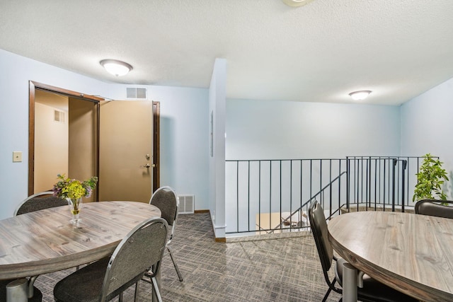 dining space with dark colored carpet and a textured ceiling