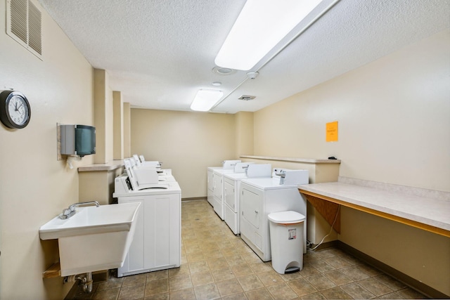 washroom with washer and clothes dryer, a textured ceiling, and sink