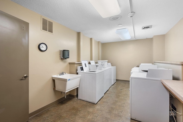 laundry area featuring a textured ceiling, washing machine and dryer, and sink