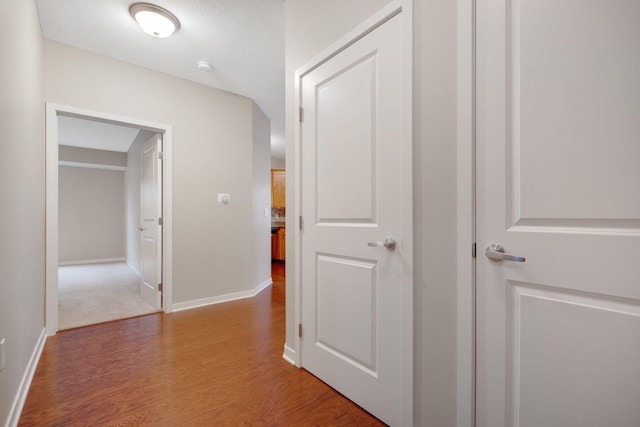 hall with light wood-type flooring and a textured ceiling