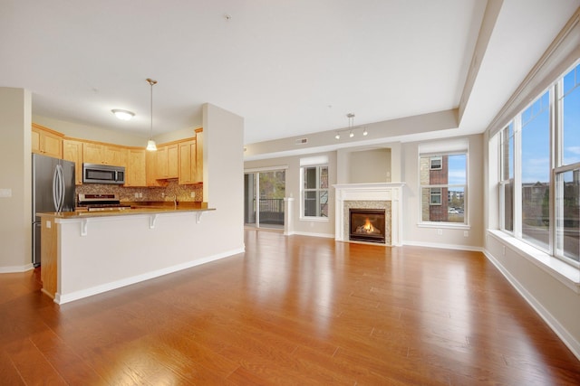 kitchen with kitchen peninsula, a kitchen bar, stainless steel appliances, decorative light fixtures, and plenty of natural light