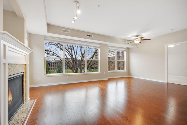 unfurnished living room featuring hardwood / wood-style floors, ceiling fan, and a premium fireplace