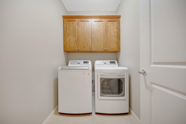 washroom with washing machine and clothes dryer and cabinets