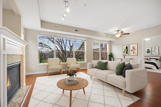 living room featuring a fireplace, wood-type flooring, and ceiling fan