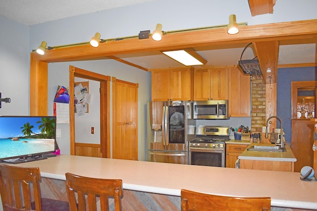 kitchen featuring kitchen peninsula, sink, a textured ceiling, and appliances with stainless steel finishes