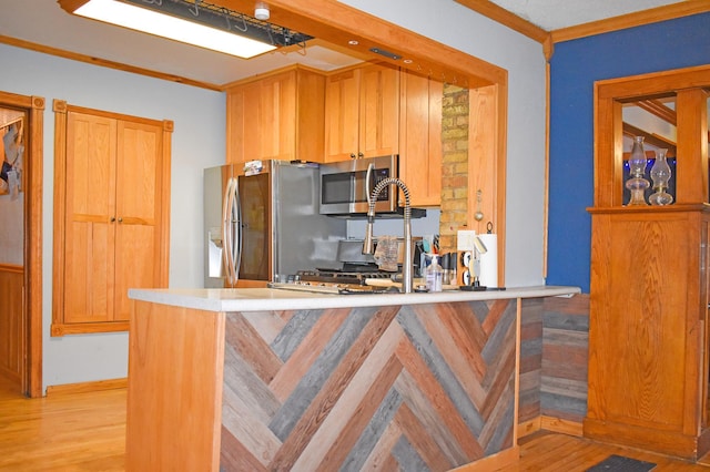 kitchen with kitchen peninsula, ornamental molding, stainless steel appliances, and light wood-type flooring