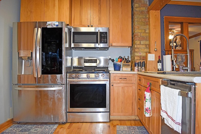 132 6th St NE, Crosby, MN 56441 - kitchen featuring appliances with stainless steel finishes, a sink, light wood-type flooring, and light countertops