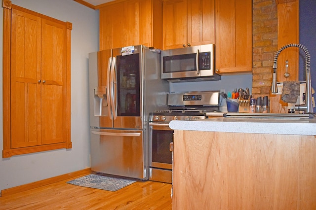 132 6th St NE, Crosby, MN 56441 - kitchen featuring appliances with stainless steel finishes, light wood finished floors, a sink, baseboards, and light countertops