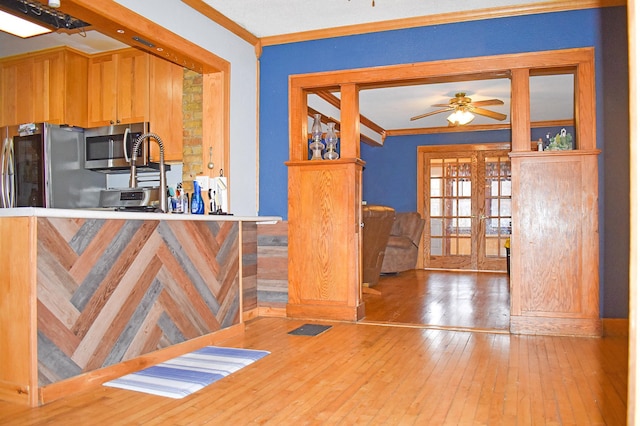 kitchen featuring french doors, ornamental molding, stainless steel appliances, ceiling fan, and wood-type flooring